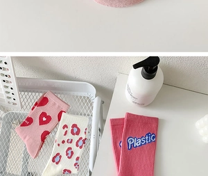 Detail of pink cotton crew socks featuring cute heart patterns and letter embroidery