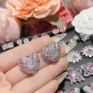 Macro detail of heart-shaped earrings with pink teardrop gems and pavé zircon stones