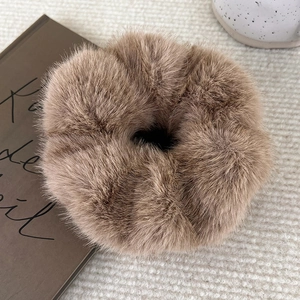 Close-up of soft brown faux mink fur scrunchie on a vintage book with warm autumn vibes