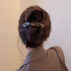 Elegant tortoiseshell spring hair clip shown on a low bun hairstyle for women