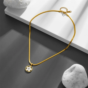 Goldene Schlangenkette aus Edelstahl mit Kleeblatt-Anhänger aus weißer Muschel auf Stein