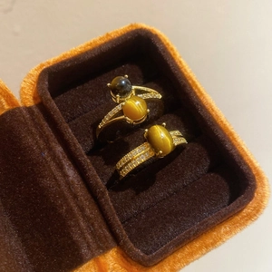 Macro detail of gold plated rings featuring brown tiger eye stones and zircon pave setting