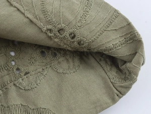Detailed macro view of olive green embroidered eyelet cotton fabric texture and stitching
