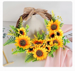 Detail of sunflower wreath with faux greenery and a burlap bow on dry vine base