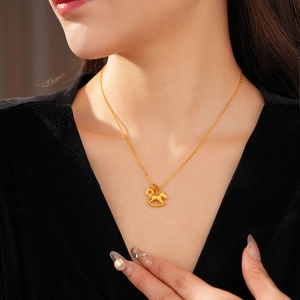 Close-up of a gold-plated rocking horse pendant with coin motifs on a delicate chain