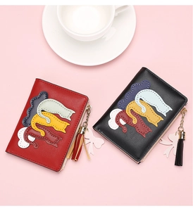 Detailed view of red and black wallets with tassel pendants on a pink background