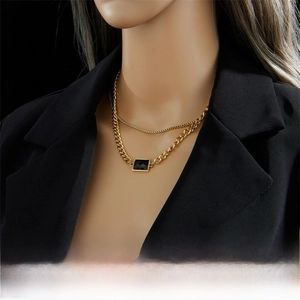 Detail of double-layer gold chain necklace with black rectangular gemstone on model