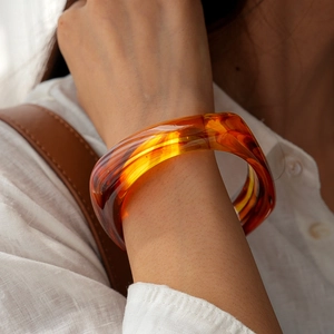 Close-up of amber acrylic resin bangle with natural swirl texture on model wrist