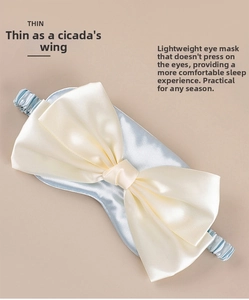 Macro view of light blue satin sleep mask with large cream bow and ruched elastic strap
