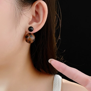 Close-up of a double ball earring with leopard print on a black gradient background