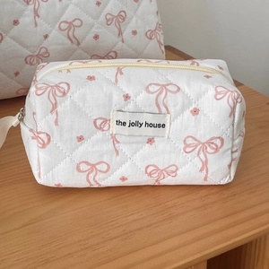 Quilted white cotton makeup bag with pink floral and bow patterns and zipper