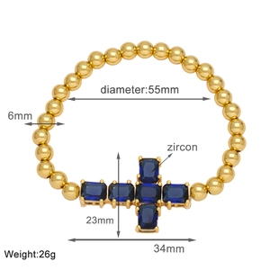 Detail shot of golden beaded bracelet showing dimensions and blue zircon cross pendant