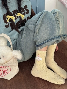 Close-up of yellow mid-calf socks with colorful speckles and cute cartoon embroidery