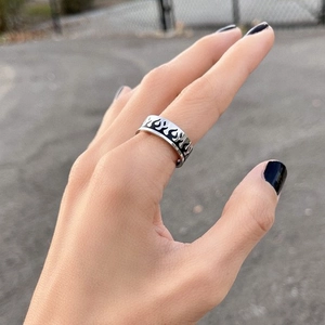 Detail of silver titanium ring with black flame pattern worn on model's hand
