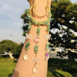 Detail of arm cuff with green crystal chips and acrylic butterfly charms in sunlight