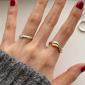 Detail of minimalist 925 sterling silver rings with stackable wave and plain band designs