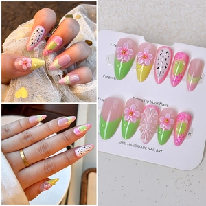 Macro detail of almond press-on nails with 3D pink petals and dragon fruit seed patterns