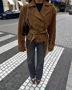 Detail of a brown faux suede jacket featuring a notched lapel and a tied waist belt