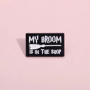 Broche en émail balai magique avec texte humoristique sur fond rose pastel uni