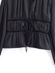Detailed view of black pleated blouse showing drawstring waist and velvet trim accents