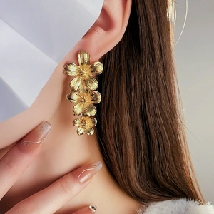 Close-up of vintage golden flower tassel earrings worn by a model in soft lighting