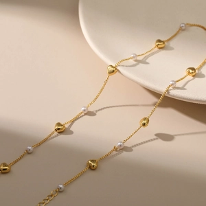 Elegante goldene Herz- und Perlenkette für Damen mit verstellbarer Kette auf Tablett