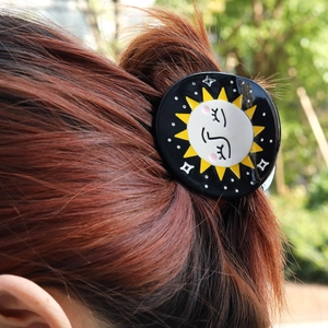 Acetate hair claw clip with celestial sun and moon pattern on elegant hair bun
