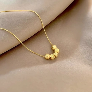 Close-up of vintage gold ball pendants on a fine box chain over luxury silk fabric