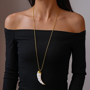 Detailed close-up of a vintage horn pendant necklace with white finish on a female model