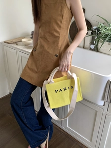 Detail of yellow woven tote bag with Paris text and long shoulder strap for beach