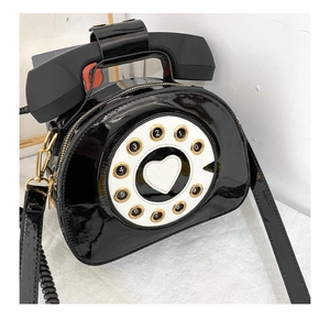Macro shot of creative retro telephone crossbody bag in black patent leather with golden zipper