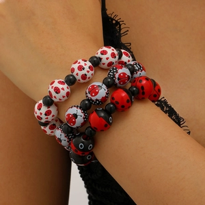 Détail de bracelets perlés avec motifs coccinelle et cœur en rouge noir et blanc