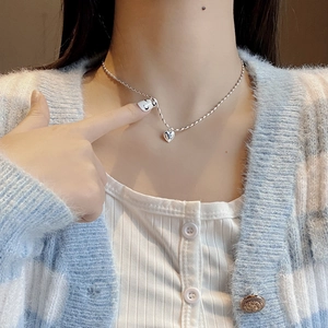 Minimalist 925 sterling silver heart necklace on a model wearing a plaid cardigan