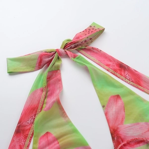 Detailed close-up of a floral mesh dress featuring a soft pink and green bow tie