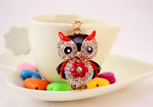 Detail of owl keychain with red rhinestones and enamel hanging on a ceramic cup