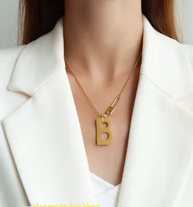 Détail d'un collier en acier titane doré avec pendentif lettre B et épingle à nourrice Love