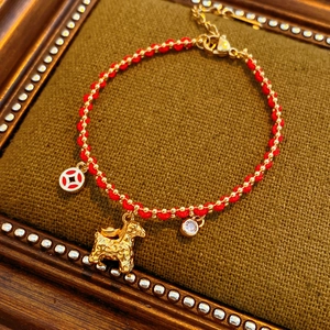 Detailed shot of 18K gold plated red rope bracelet with horse charm and zircon pendants