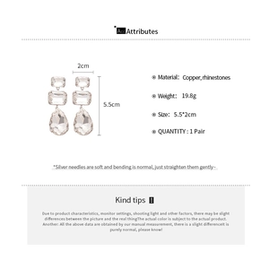 Detailed view of silver needle drop earrings with square rhinestones measuring 5.5 by 2 cm