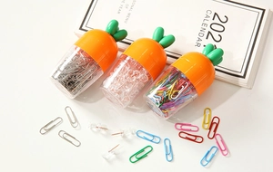 Close-up of carrot-shaped office kit with metal paperclips and transparent push pins