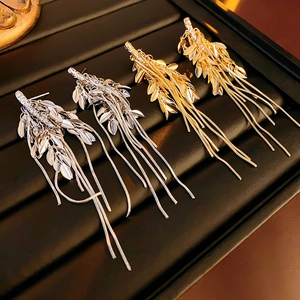 Detailed view of elegant gold and silver wheat tassel earrings on a display tray