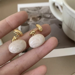 Detailansicht der cremefarbenen Ohrringe mit Vintage-Goldmetall und Marmortextur