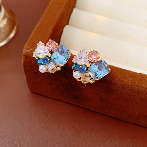 Detailed shot of irregular geometric earrings with colorful zircons on a velvet stand