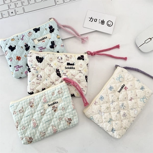 Close-up of quilted floral cotton pouches with colorful zipper pulls on a desk