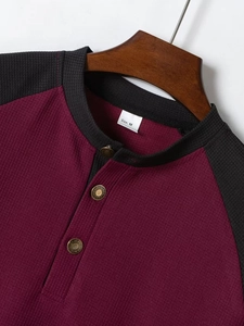 Dettaglio del tessuto a nido d'ape e scollo a V su una t-shirt bordeaux color-block da uomo