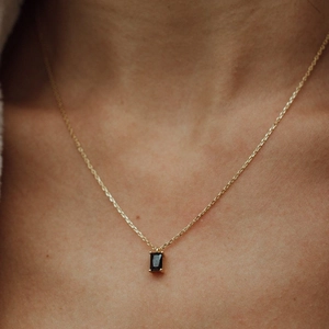 Gros plan d'un collier plaqué or 18 carats avec un pendentif rectangle en pierre noire