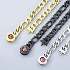 Detailed macro view of Figaro chain necklaces in gold, black, and silver with red gem clasps