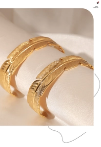 Detailed view of golden feather-shaped titanium steel bracelets with embossed textures