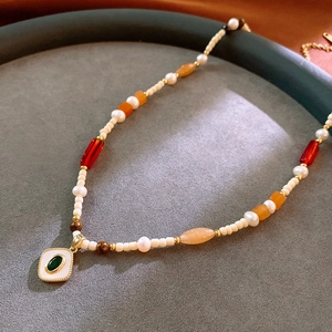 Macro detail of aquamarine and pearl beaded necklace with vintage gold pendant