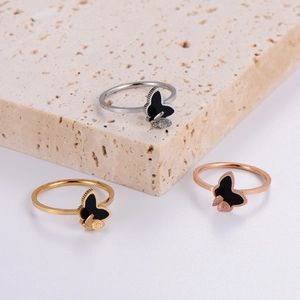 Three minimalist butterfly rings in gold, silver, and rose gold on a stone plate