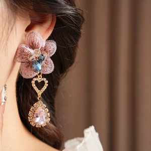 Detailed view of vintage asymmetric earring with pink embroidered flower and pear-cut crystal